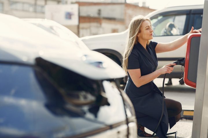 modern woman using station for charging electromobile