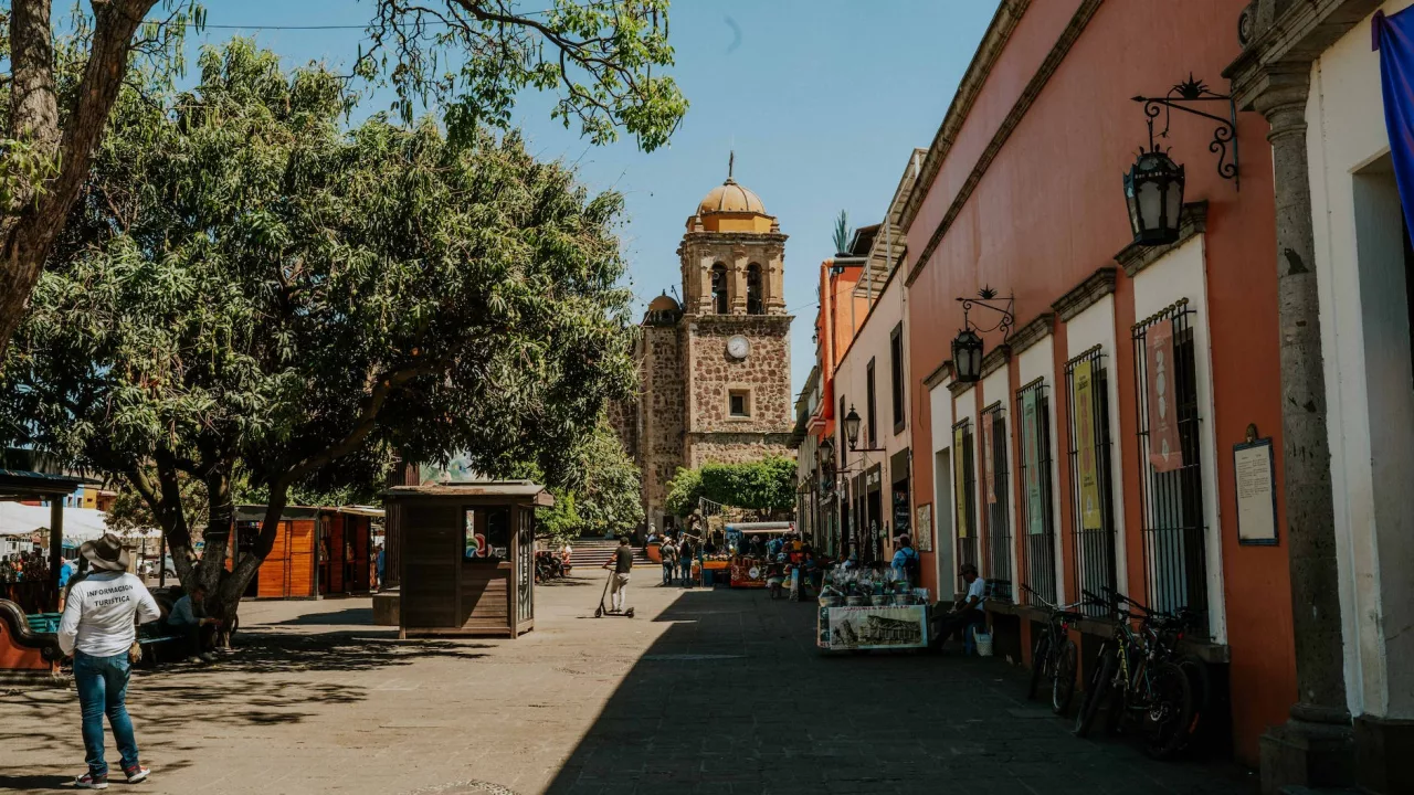 a street with people walking and a church in the background