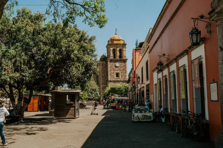 a street with people walking and a church in the background