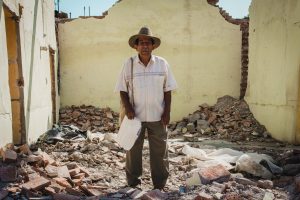 man standing on ruin of house