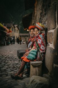 peruvian girls wearing traditional clothing sitting by a wall