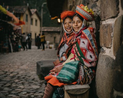 peruvian girls wearing traditional clothing sitting by a wall