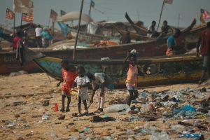 children playing on the beach near boats and trash
